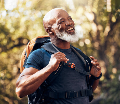 Nature, fitness and black man hiking with a backpack in a forest for exercise, health and wellness. Sports, athlete and happy senior African male hiker trekking in the woods on an adventure trail.