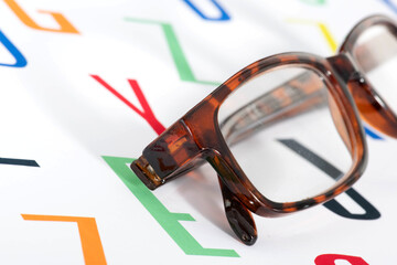 Eine Brille auf einem Hintergrund aus bunten Buchstaben