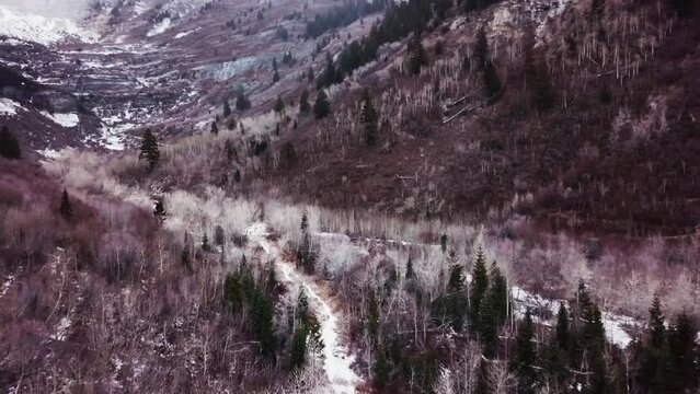Snowy Trail Between Steep Mountain Slopes In Hobble Creek Canyon, Wasatch Range, Utah. aerial pullback
