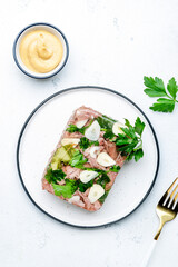 Aspic meat, cold boiled beef in spiced jelly broth on plate, dijon mustard dressing. White kitchen...
