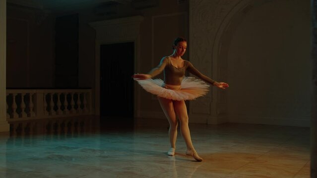 Cinematic shot of graceful female ballet dancer on choreography rehearsal in theater lobby, practicing elegant movements. Ballerina in tutu before performance in opera. Classical theatrical ballet art