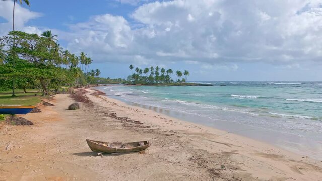 Slow aerial flight over sandy beach of PLAYA LOS COQUITOS with tropical trees, boats and blue Caribbean Sea 