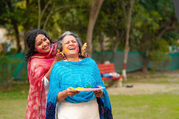 Indian woman applying color on face each other and celebrating holi festival.