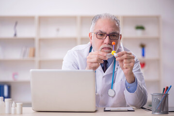 Old male doctor holding molecular model in the clinic