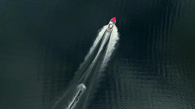 Top down drone shot of a person riding a trick ski behind a ski boat on a lake in Florida