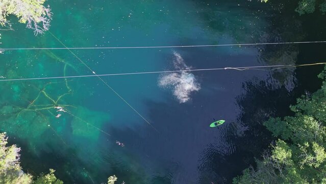 Unrecognizable person jumps from a rope in blue waters of Dudu lagoon, Cabrera in Dominican Republic. Aerial top-down directly above