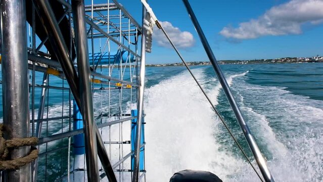 Shark cage diving boat runs out to sea - backwards view of shark cage and wake