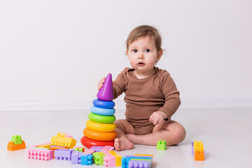 adorable baby in brown shirt playing with toys, card, banner, space for text