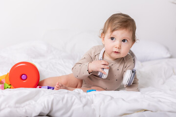 cute baby playing with colorful toys and headphones on blanket, banner, space for text