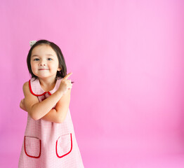 Pretty little girl crosses her arms while pointing off to the side and smiling. 