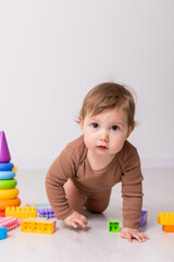 adorable baby in brown shirt playing with toys, card, banner, space for text