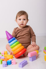 adorable baby in brown shirt playing with toys, card, banner, space for text