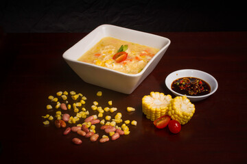 hot corn soup served with soy sauce and red chilies 