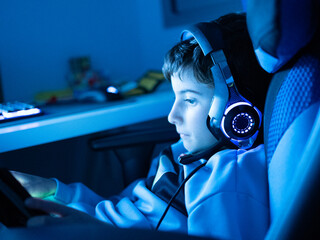 Portrait of kid playing video game at neon light background - concept of entertainment technology
