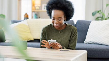 Excited black woman chatting in dating app using her phone at home. A young female online shopping happy about a purchase in her house. A lady celebrating after reading good social media news - obrazy, fototapety, plakaty