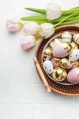 Easter golden eggs and pink tulips on white tile  background.