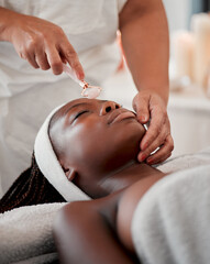 Black woman, face roller and luxury spa treatment of a young female ready for facial. Skincare, rose quartz tool and wellness clinic with client feeling calm and zen from massage and dermatology