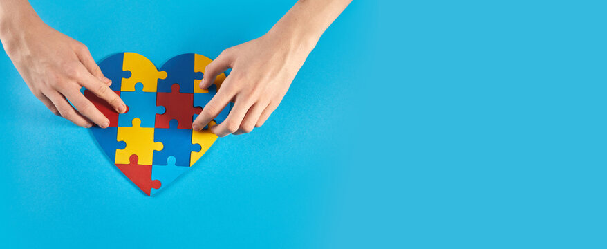 Autistic boy hands holding jigsaw puzzle heart shape. World Autism Awareness Day