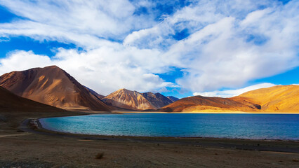 Fototapeta na wymiar Panorama landscape of Pangong lake with mountain background under winter blue sky.Pangong tso with cloudy sky.Natural beauty of Ladakh,India. Famous tourist place in the world.China and India border.