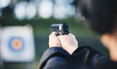 Hands, gun and aim at shooting range target with weapon outdoor for security training. Person learning defence for safety and focus for sport competition or game with handgun gear and bullseye board