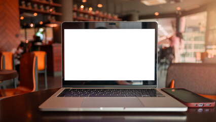Selective focus of laptop with blank screen on wood table in blurry background in cafe.