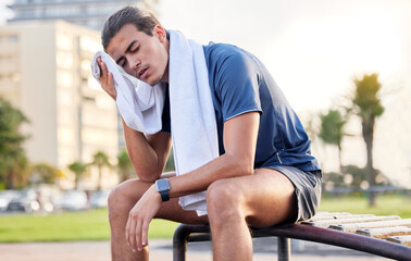 Fitness, exercise and tired man with a towel on park bench to relax or rest after running for...