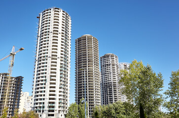 Tower crane building a house. Concrete buildings under construction against sky. Construction site