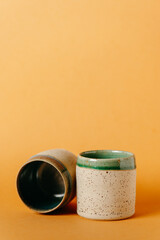 corso di ceramica, bicchieri in ceramica fatti al tornio a mano. sfondo neutro colorato. bicchieri e recipienti per colazione pranzo o cena, tisane, momento di relax
