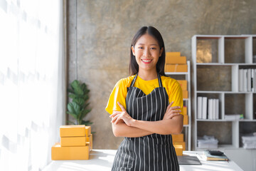 Young pretty asian start up business woman in apron working with online parcel box warehouse...