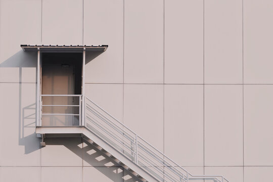 Sunlight And Shadow On Surface Of Exit Door With Fire Escape On Gray Aluminum Composite Tile Wall Of Modern Industrial Building