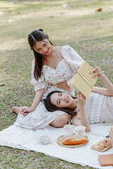 Two pretty asian friends woman picnic at park outdoor in relax time holiday, holiday recreation concept.