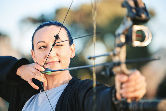 Archery bow, woman aim and shooting range for competition, game or practice at an outdoor sports or park. Hunter or person face with arrow for gaming, adventure and hunting with focus on target