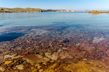 Cala virgen del norte de Menorca con aguas transparentes, donde se aprecia el fondo marino  - obrazy, fototapety, plakaty