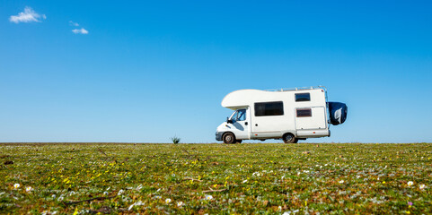 motor home in green meadow against blue sky- travel,  vacation,  adventure