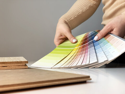 Close-up of interior designer woman choosing samples of wall paint. Work with color palette. Concept: interior designer looking at color swatch for creating project