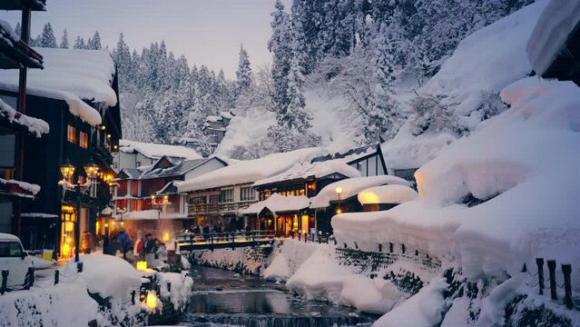4K Landscape of Beautiful nature in winter season. Ginzan Onsen area  in Yamagata prefecture, Japan covered in snow and people tourist walking down street in snowing day on winter holiday vacation.