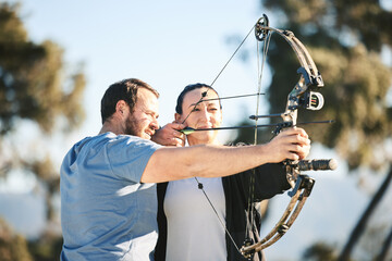 Archery, shooting range and sports training to aim with a woman and man outdoor for target...