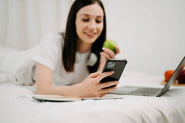 Fototapeta premium Beautiful woman resting and watching movie in bed at bedroom in morning Lifestyle at home