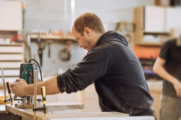 Сarpenter working with an electric milling, sawing wood board with.