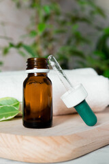 Glass dropper bottle mockup. Body care and spa. Natural cosmetics. skin care bottle. bottle for essential oils and cosmetics lies on a white towel. Dropper. Spa still life with towel, wooden board
