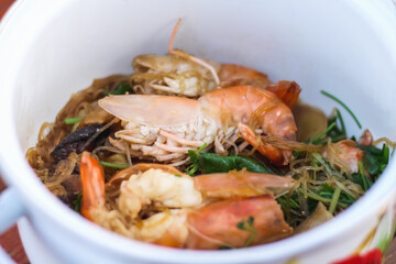 Steamed Prawns with Vermicelli in white hot pot Thai food background