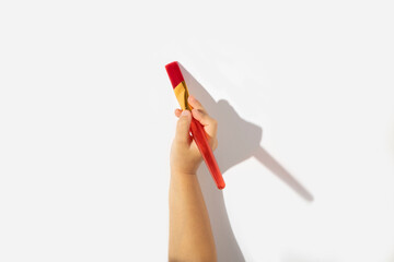 Child's hand holds a paintbrush on a white background. Top view, flat lay