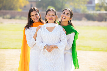 Indian Independence day or Republic day concept. Three happy young beautiful woman wearing traditional white dress standing together at park having fun.