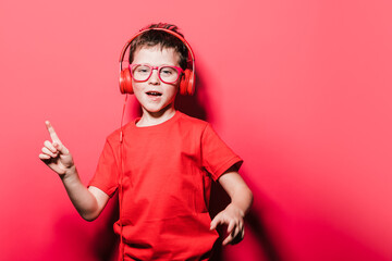 Energetic boy in headphones singing against red background