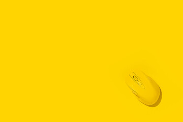 Yellow wireless computer mouse on a yellow background. Top view, flat lay