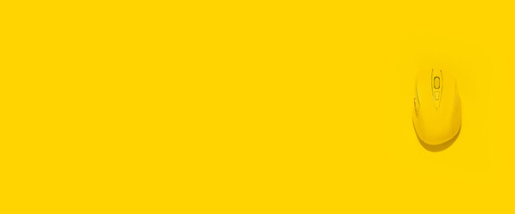 Yellow wireless computer mouse on a yellow background. Top view, flat lay. Banner