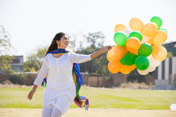 Beautiful happy young indian girl wearing traditional white kurta dress running with tricolor...