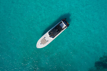 Big white motor boat anchored in the blue sea top view. White modern boat with motor on blue...