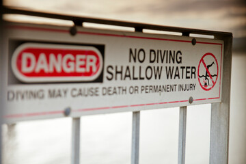 A sign warning users not to dive into the shallow water.
