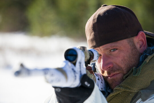 A hunter  takes aim with his rifel.